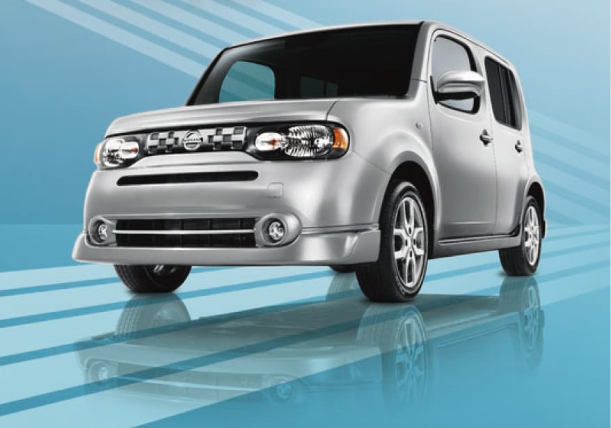 Silver Nissan Cube driving on blue background