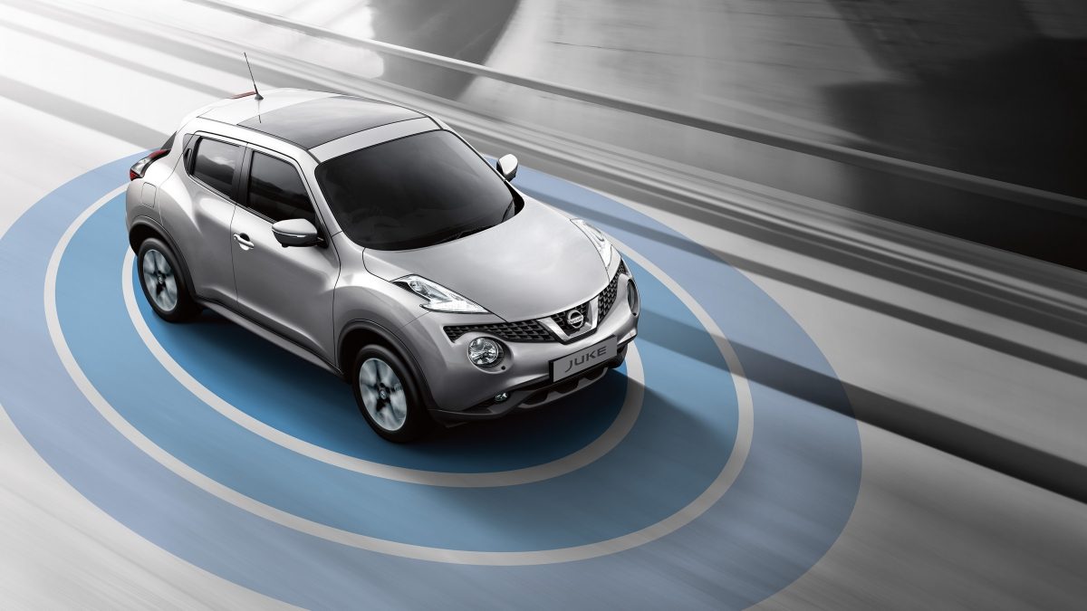 A top down view of a gray Nissan JUKE driving down a freeway with a graphic demonstrating the Around View Monitor technology