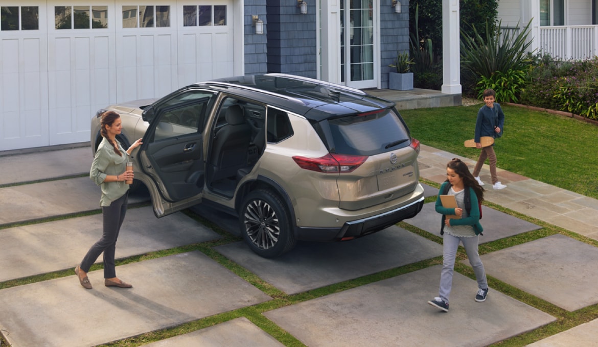 Rear view of 2024 Nissan Rogue parked in front of a house with the back door open