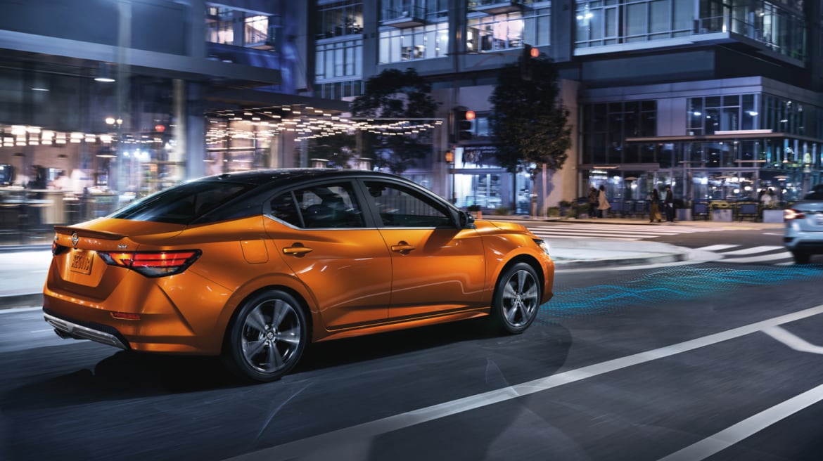 2024 Nissan Sentra in orange driving through city street at night